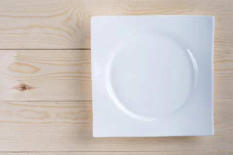Flat lay above empty white plate on the wooden boards table background Stock Photos