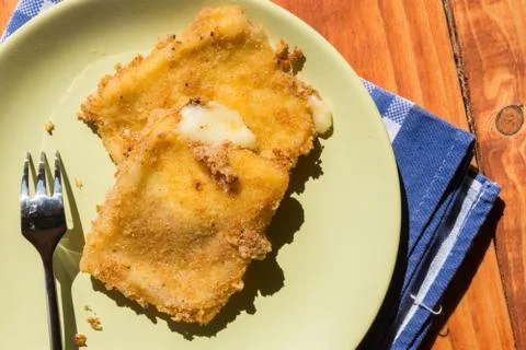 Flat lay above fried cheese on the plate with fork on the wooden table Stock Photos