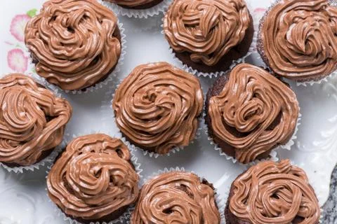 Flat lay above full plate of chocolate cup cakes with ganache chocolate cream Stock Photos