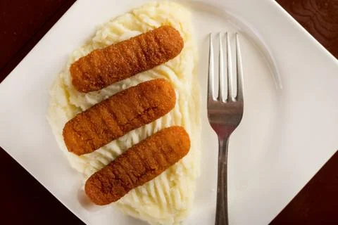 Flat lay above plate served with fish sticks and mashed potatoes Stock Photos