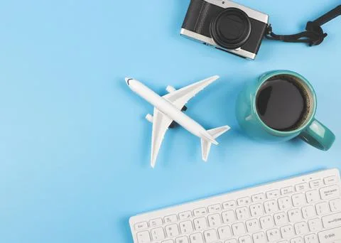 Flat lay of airplane model, computer keyboard,  camera and blue cup of black  Stock Photos