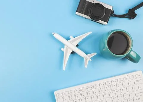 Flat lay of airplane model, computer keyboard, camera and blue cup of black.. Stock Photos