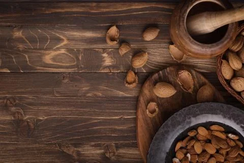 Flat lay of almonds in black plate with other accessories on brown wooden bac Stock Photos