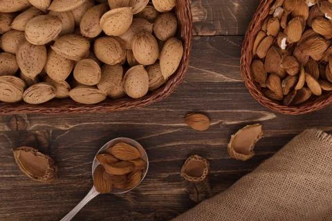 Flat lay of almonds in the wicker plates with other accessories on brown wood Stock Photos