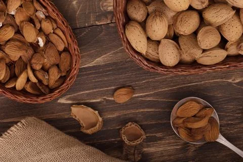 Flat lay of almonds in the wicker plates with other accessories on brown wood Stock Photos