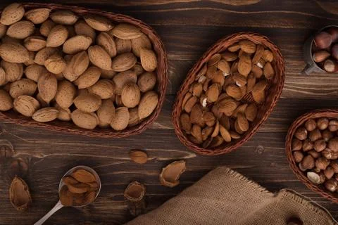Flat lay of almonds in the wicker plates with other accessories on brown wood Stock Photos