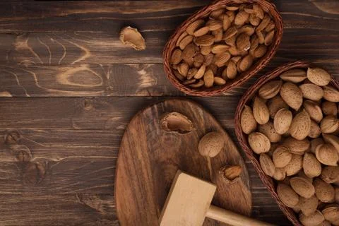 Flat lay of almonds in the wicker plates with other accessories on brown wood Foto stock