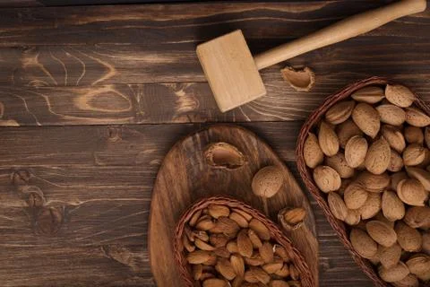 Flat lay of almonds in the wicker plates with other accessories on brown wood Stock Photos