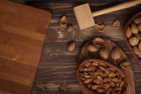 Flat lay of almonds in the wicker plates with other accessories on brown wood Stock Photos