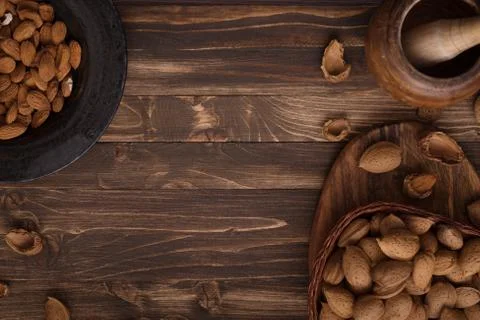 Flat lay of almonds in the wicker plates with other accessories on brown wood Stock Photos