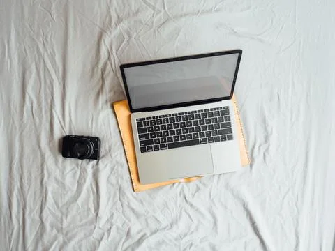 Flat lay and top view of laptop and camera on the bed. Stock Photos