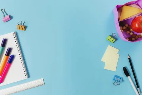 Flat lay with assorted school supplies and lunch box with sandwich, nuts, app Stock Photos