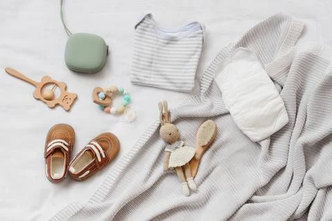 Flat lay of baby essentials including a striped onesie diaper shoes wooden to Stock Photos