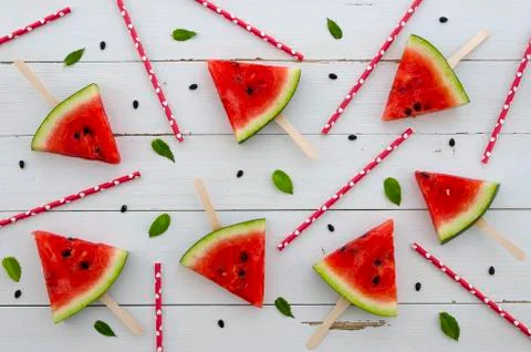 Flat lay background watermelon red slice popsicles arranged with juice straw and Stock Photos