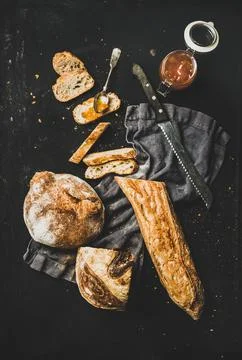 Flat-lay of baguette, bread loaf and apricot jam Stock Photos