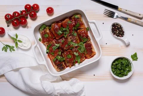 Flat lay with baked cabbage rolls in white square baking pan Stock Photos