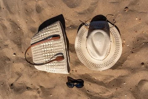 Flat Lay of Beach Accessories Straw Hat Woven Tote and Sunglasses on Sand Stock-Fotos