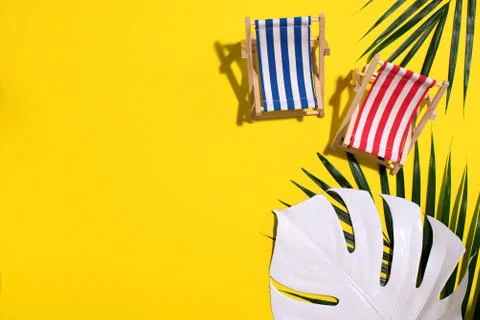 Flat lay of beach deck chairs, monstera and palm leaves on pink background with Stock Photos