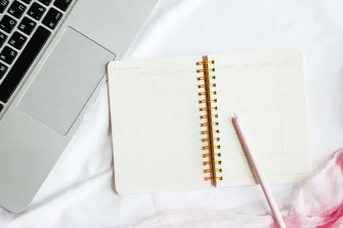 Flat lay bed workspace with laptop, planner, pen on white background. Top vie Stock Photos