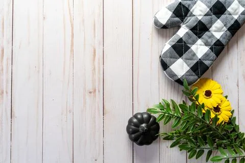 Flat lay with a black and white oven mitt, sunflowers, leaves and a black p.. Stock Photos