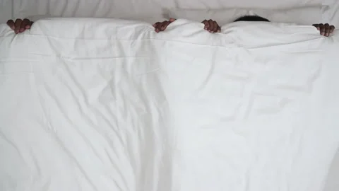 Flat lay of black couple lying in bed, emerging from white blanket and looking Stock Footage 136508135