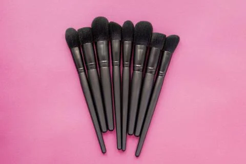 Flat lay of black makeup brushes collection on pink background Stock Photos