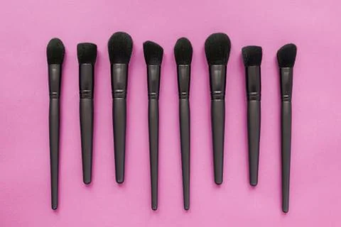 Flat lay of black makeup brushes on pink background. Top view of make-up brushes Stock Photos