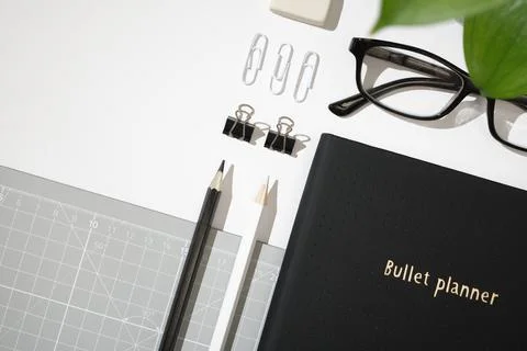 Flat lay of black planner with paper clips, binder clips, glasses, eraser, .. 스톡 사진