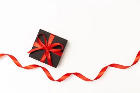 Flat lay of black present box with red bow and ribbon on the white background Stock Photos