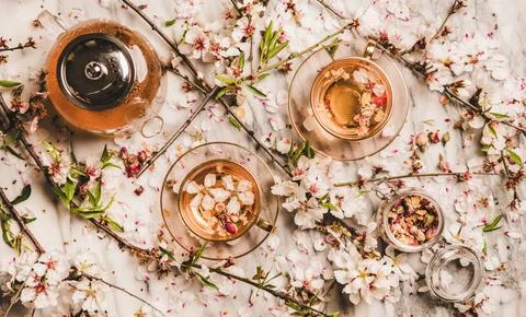 Flat-lay black tea with dry rose flowers over blossom branches Stock Photos