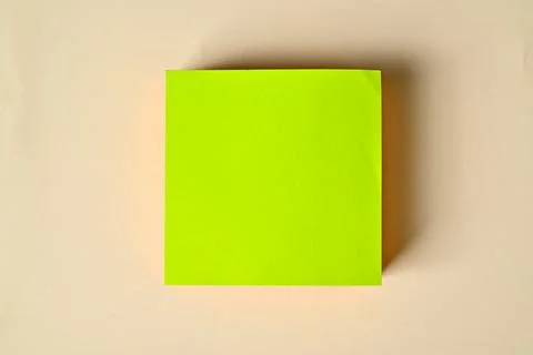 Flat lay of a blank bright green square sticky note block centered on a war.. Stock Photos