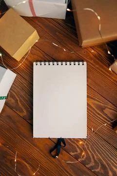 Flat lay of blank notebook and gift boxes on wood table background. Stock Photos