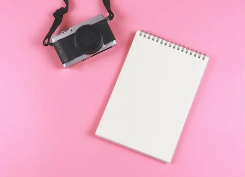 Flat lay of blank page opened notebook and camera on pink background. Stock Photos
