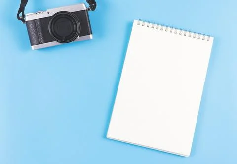 Flat lay of blank page opened notebook and camera on blue background. Stock Photos