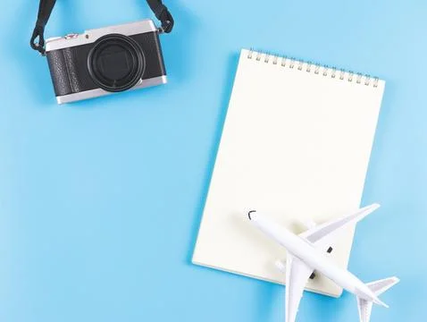 Flat lay of blank page opened notebook, airplane model and camera on blue b.. Stock Photos