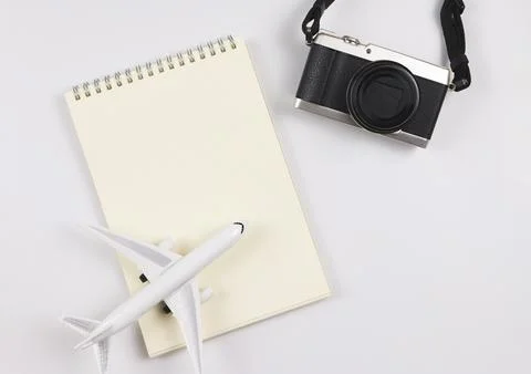 Flat lay of blank page opened notebook, airplane model  and camera on white.. Stock Photos