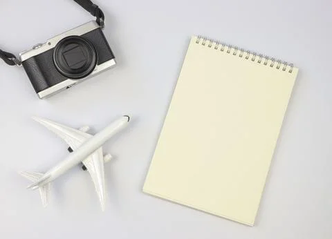 Flat lay of blank page opened notebook, airplane model  and camera on white.. Stock Photos