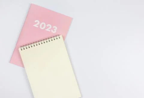 Flat lay of blank paper note book on pink diary 2023 on white background. Stock Photos