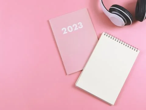 Flat lay of blank paper note book on pink diary or planner 2023 and headpho.. Stock Photos