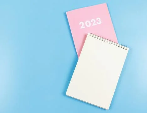 Flat lay of blank paper note book on pink diary 2023 on blue  background. Stock Photos