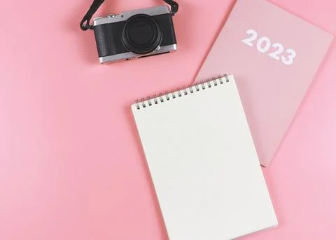 Flat lay of blank paper notebook on pink diary 2023 with camera on pink bac.. Stock Photos