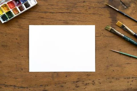 Flat lay of blank sheet of paper, watercolor palette and paint brushes on woo Stock Photos