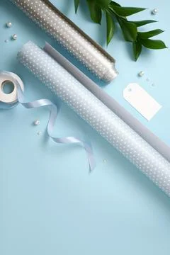 Flat lay of blue and silver dotted wrapping paper, ribbon, scissors, and labe Фото