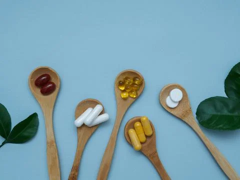Flat lay on blue background vitamin D, E, omega 3, calcium, vitamin B in wooden Stock Photos