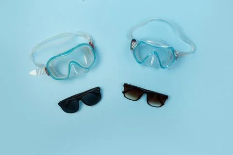 Flat lay of blue diving masks and sunglasses on isolated blue background Stock Photos