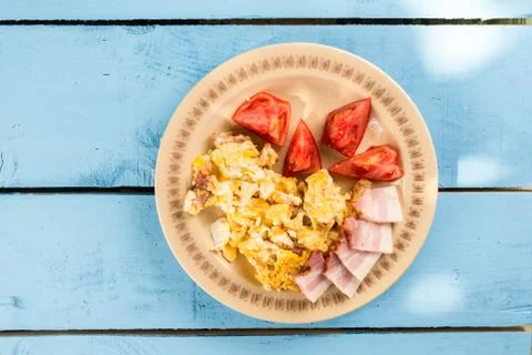 Flat lay breakfast fried eggs with raw bacon and tomato salad Stock Photos