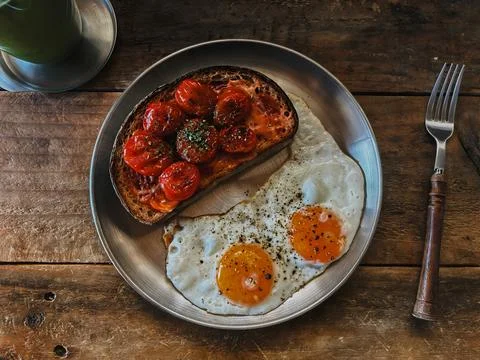 Flat Lay Breakfast Plate with Roasted Tomato Toast and Sunny Side Up Eggs Stock Photos