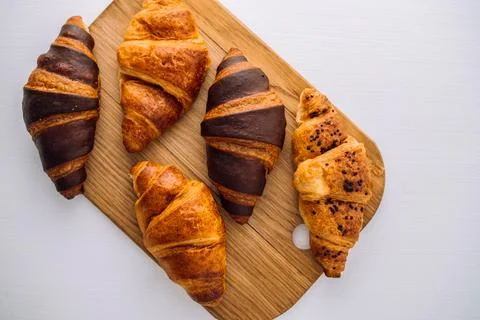 Flat lay of bunch of appetizing brown and chocolate croissants on a wooden board 写真素材