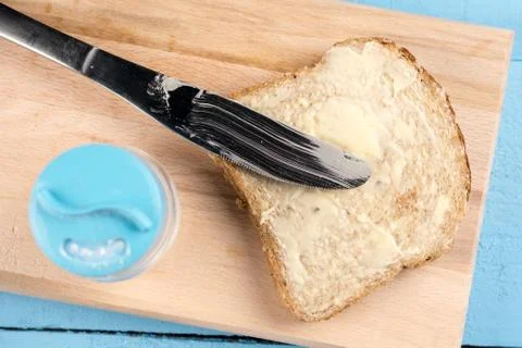 Flat lay butter spread on bread with knife and served on a wooden board Stock Photos