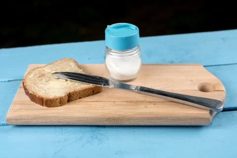 Flat lay butter spread on bread with knife and saltshaker served on a wooden  Stock Photos